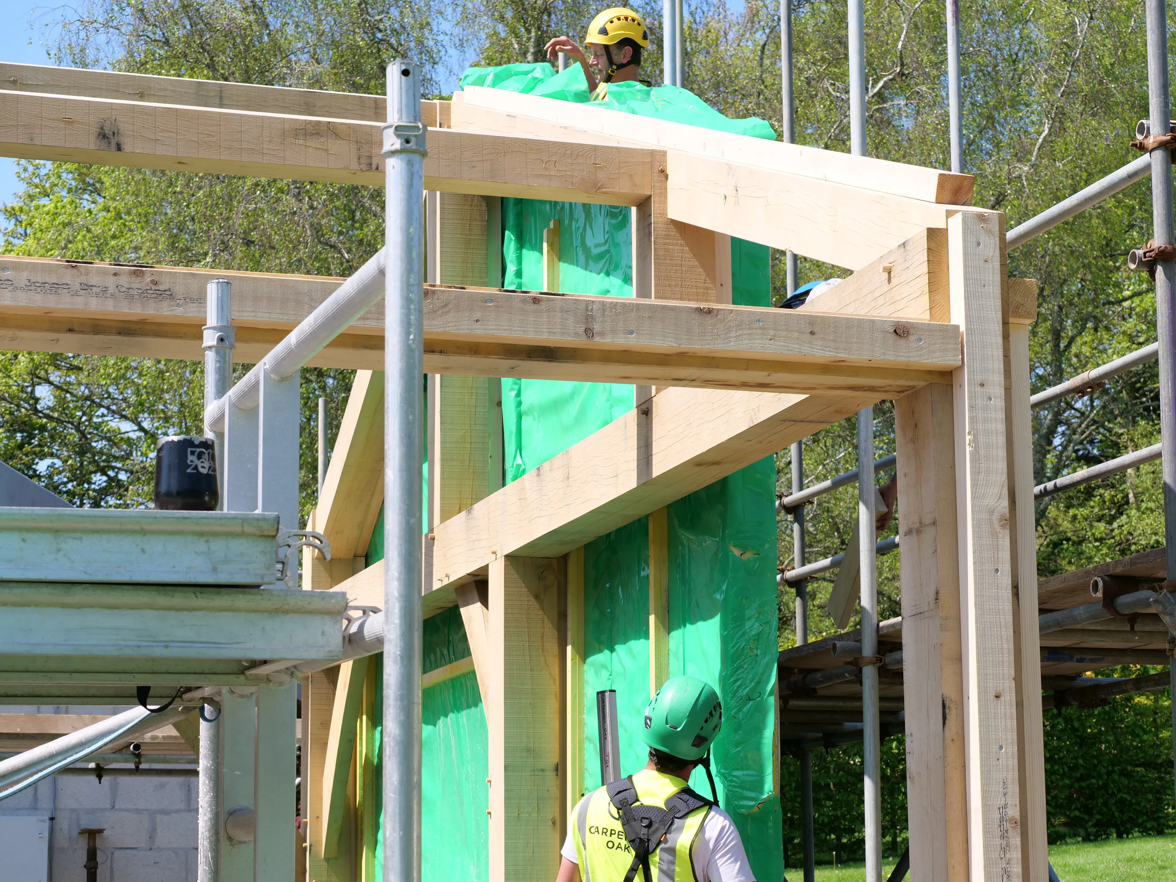 Carpenters on a construction site installing SiPs panels onto an oak frame for an extension