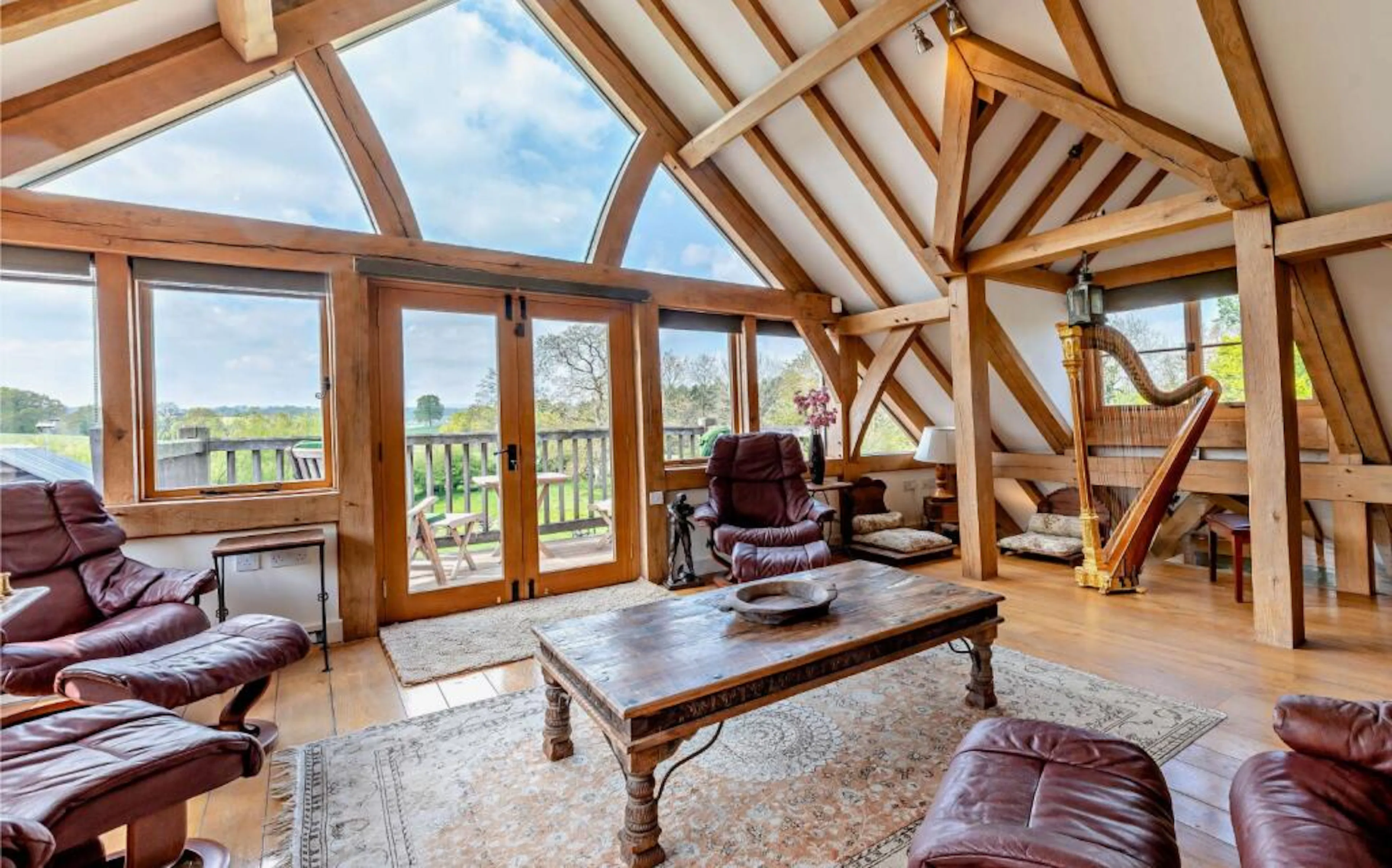 An upstairs sitting room in an oak framed extension with dormer windows and views of a large garden