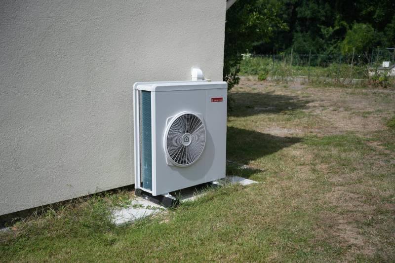 Photo d'une installation d'une pompe à chaleur, avec unité extérieure sur la façade de la maison