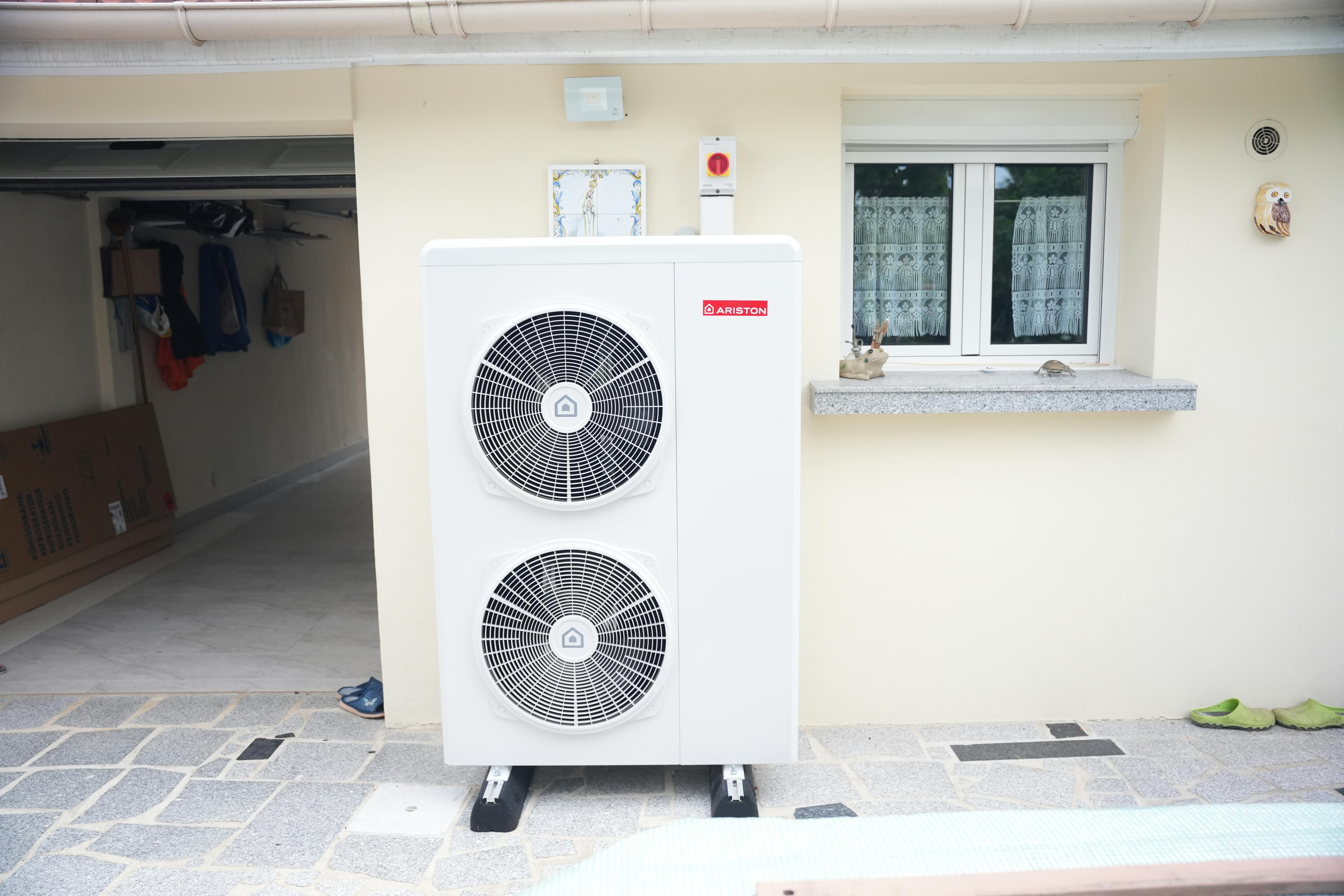 Photo d'une unité extérieure d'une pompe à chaleur Air/Eau installée devant la façade d'une maison