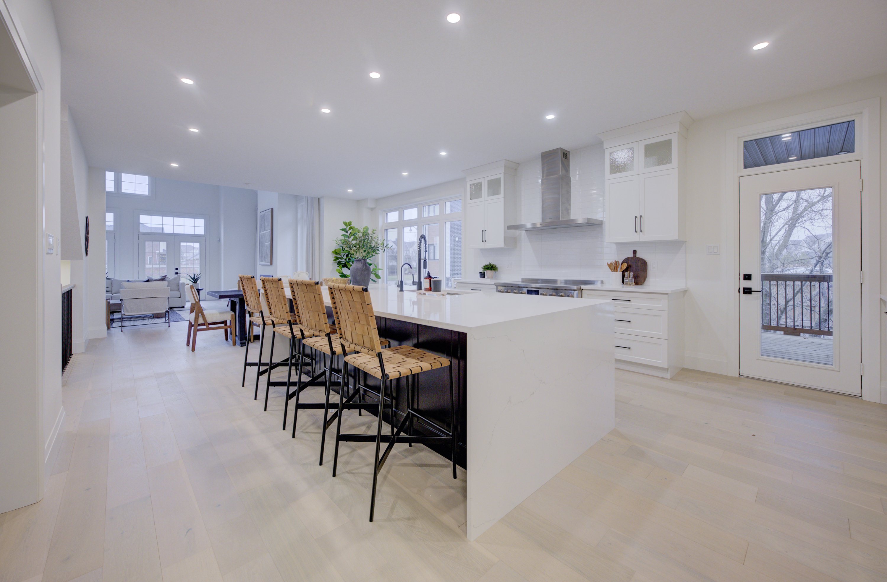 Modern kitchen with a large white island, wicker bar stools, and bright recessed lighting