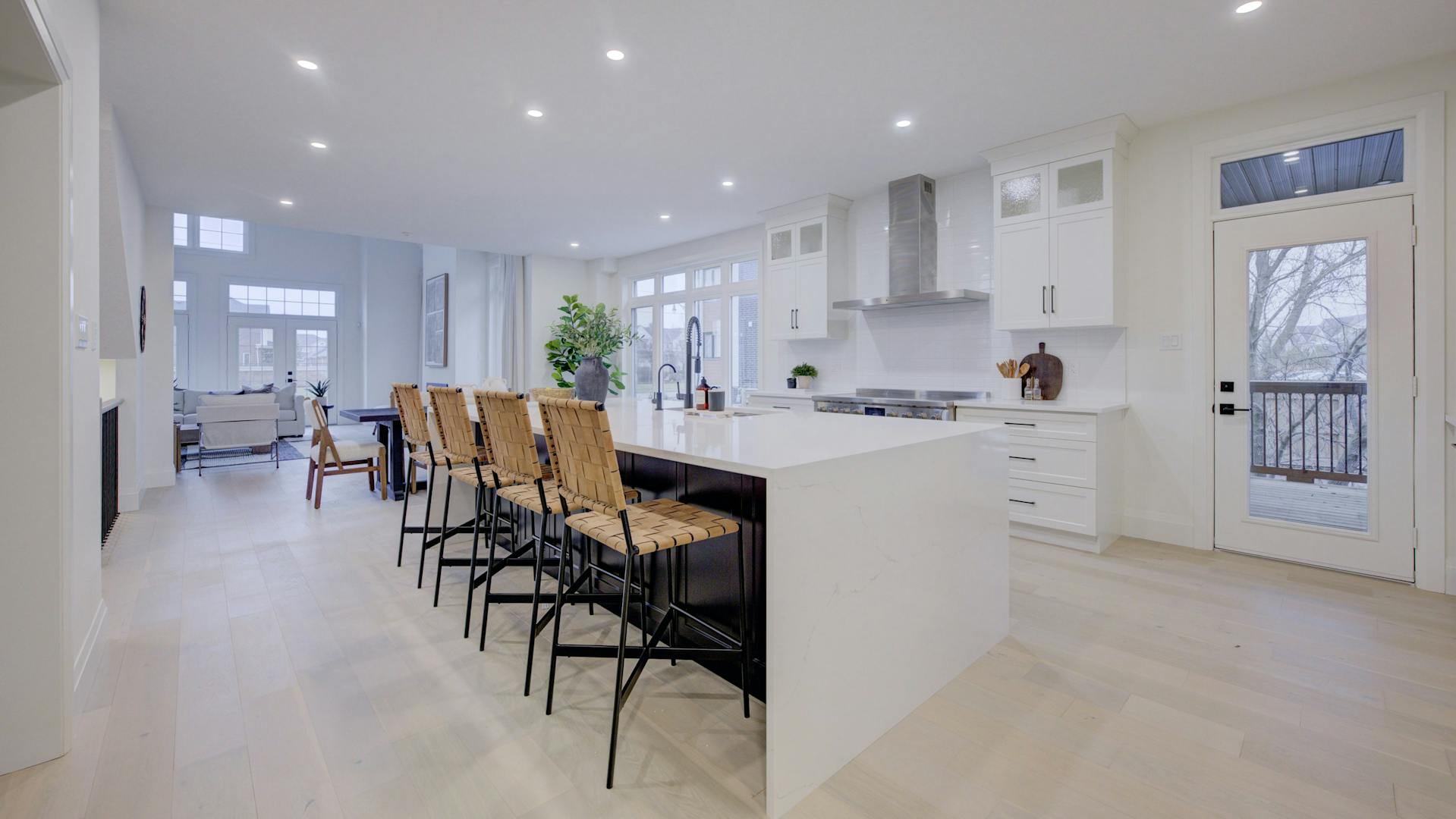 Modern kitchen with a large white island, wicker bar stools, and bright recessed lighting