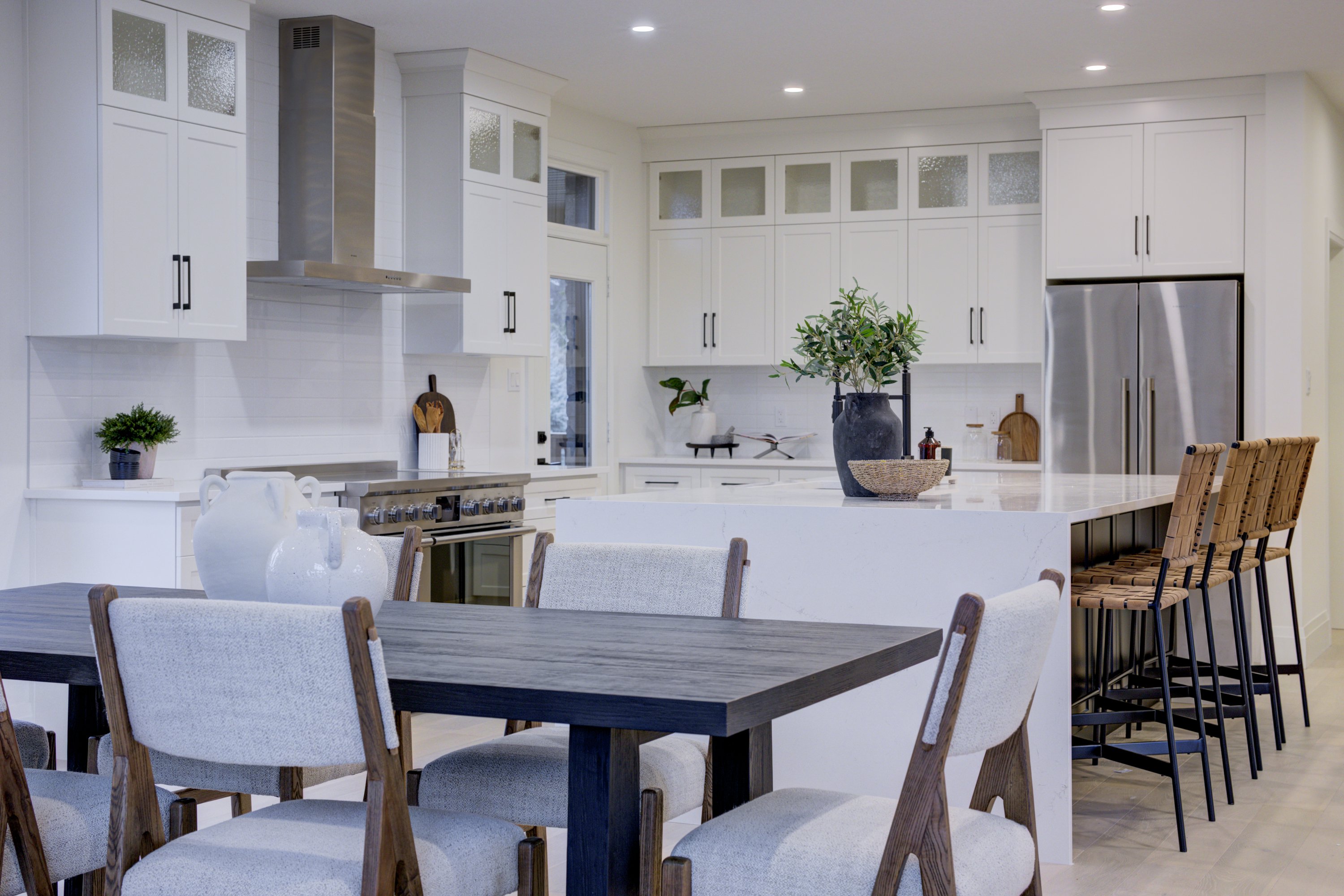 Modern kitchen with a large island, white cabinetry, stainless steel appliances, and dining area