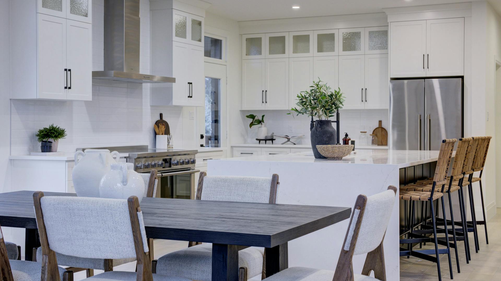 Modern kitchen with a large island, white cabinetry, stainless steel appliances, and dining area