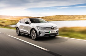 White Renault Megane Etech Electric driving on country road.