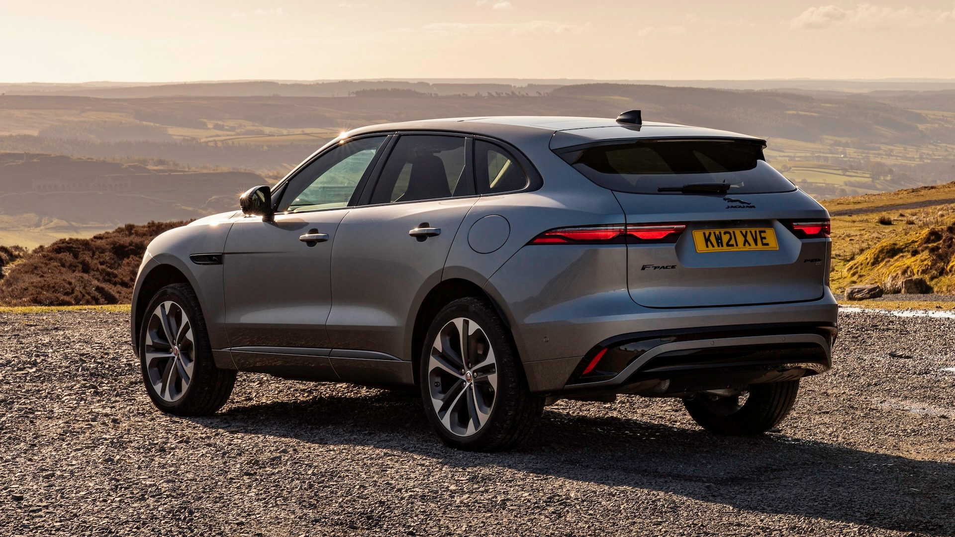 Silver 2021 Jaguar F-Pace parked on gravel, rear quarter view.