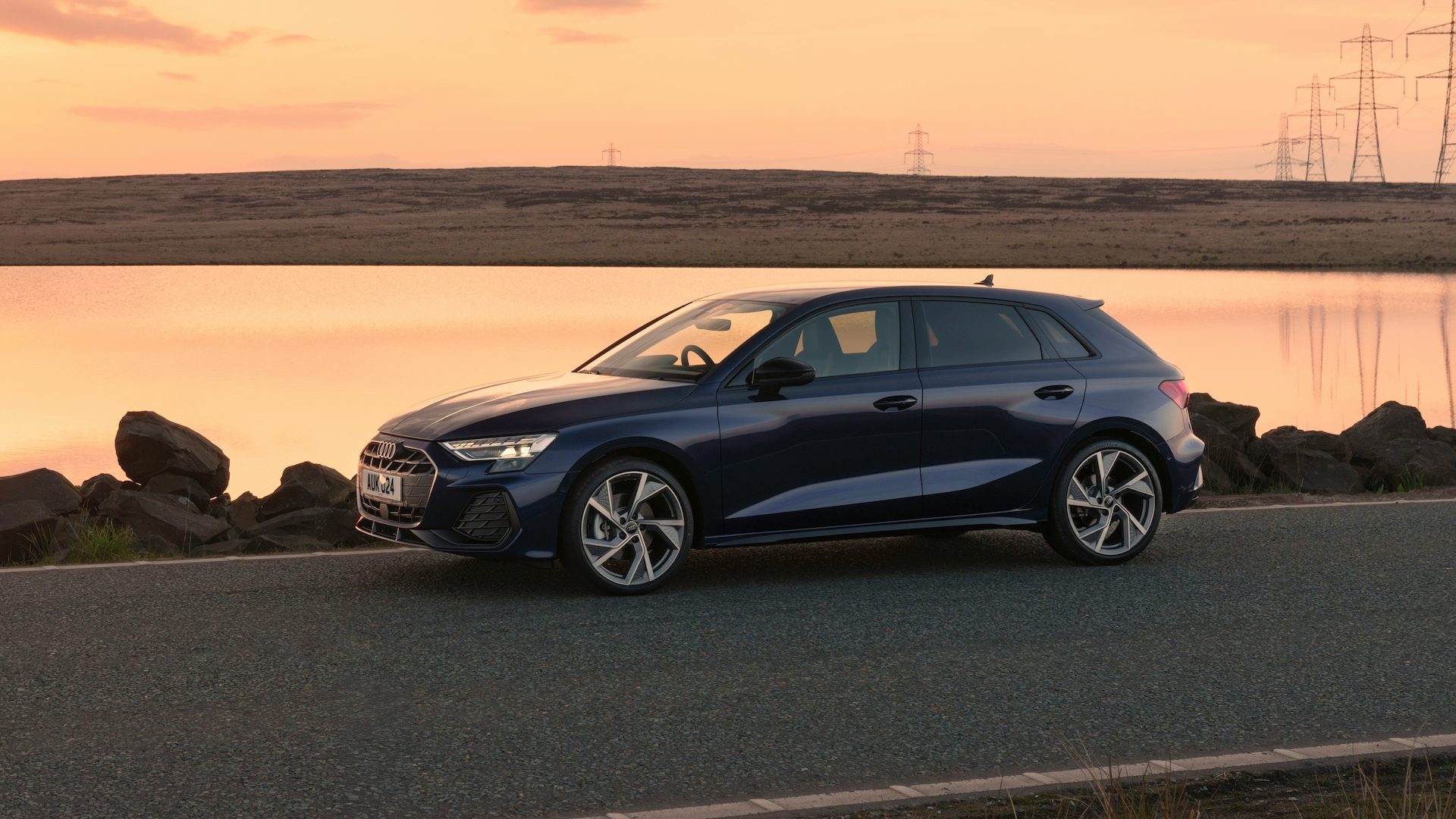 Blue 2024 Audi A3 parked beside a lake, front quarter view.