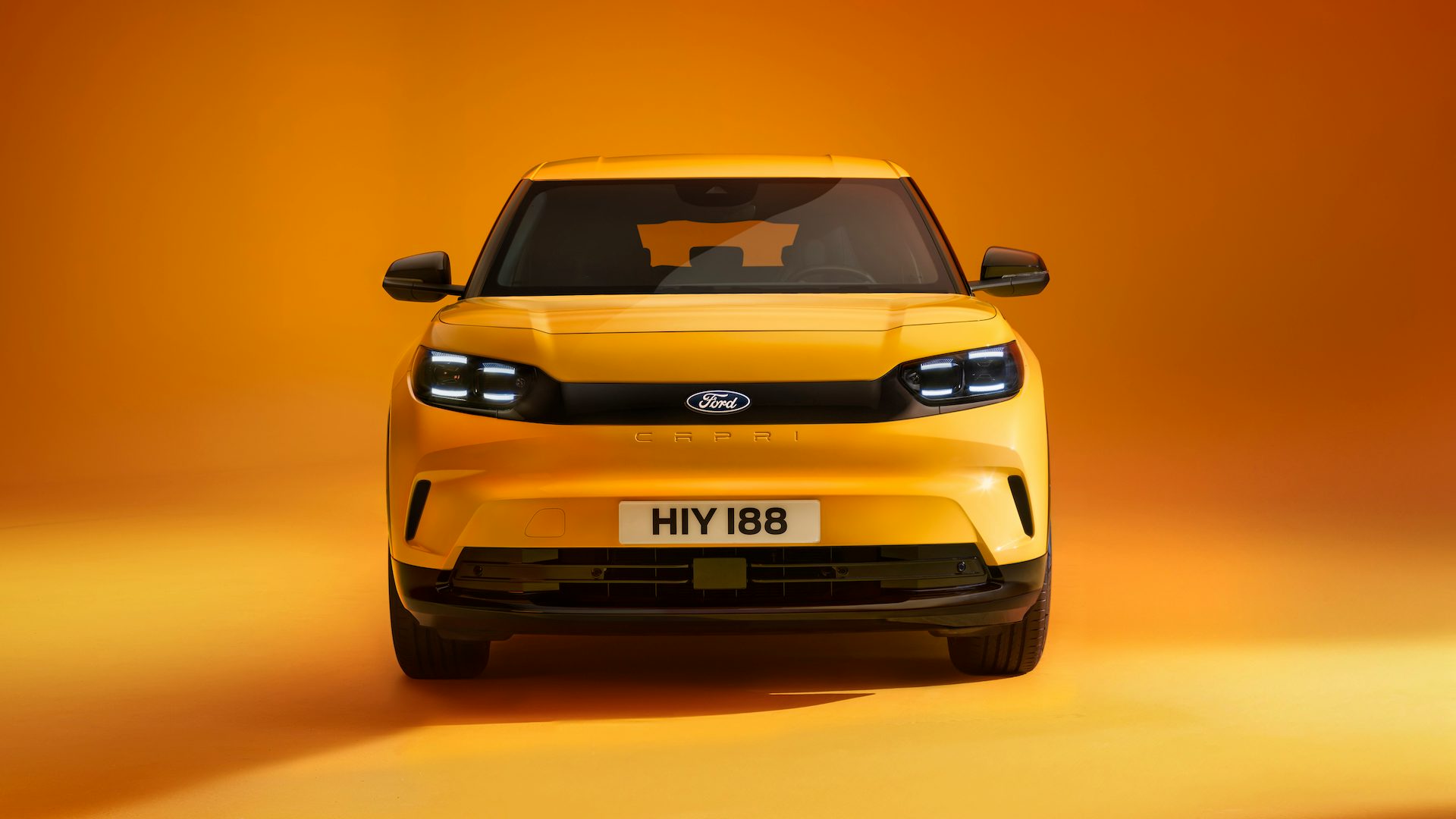 Yellow 2024 Ford Capri parked in a studio, front shot.