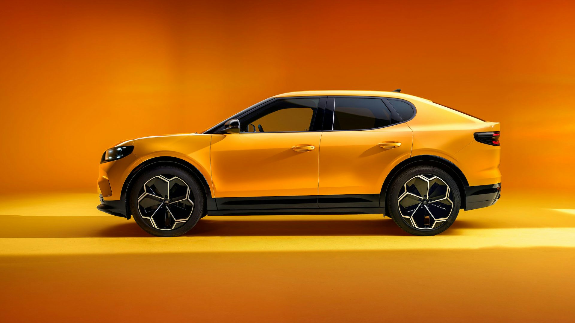 Yellow 2024 Ford Capri parked in a studio, side angle.
