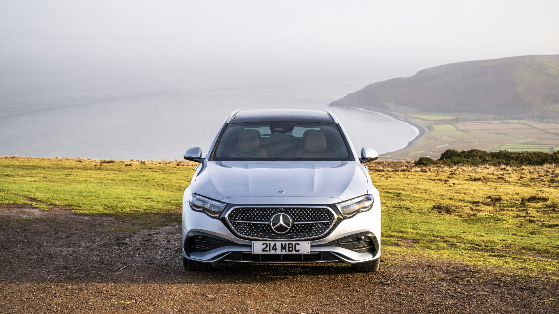 Silver 2024 Mercedes E-Class Estate parked near the coast, front view