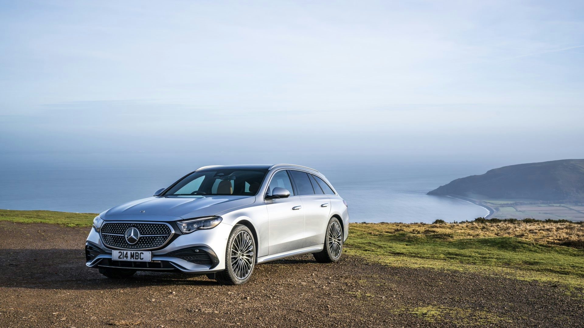 Silver 2024 Mercedes E-Class Estate parked near the coast, front quarter view