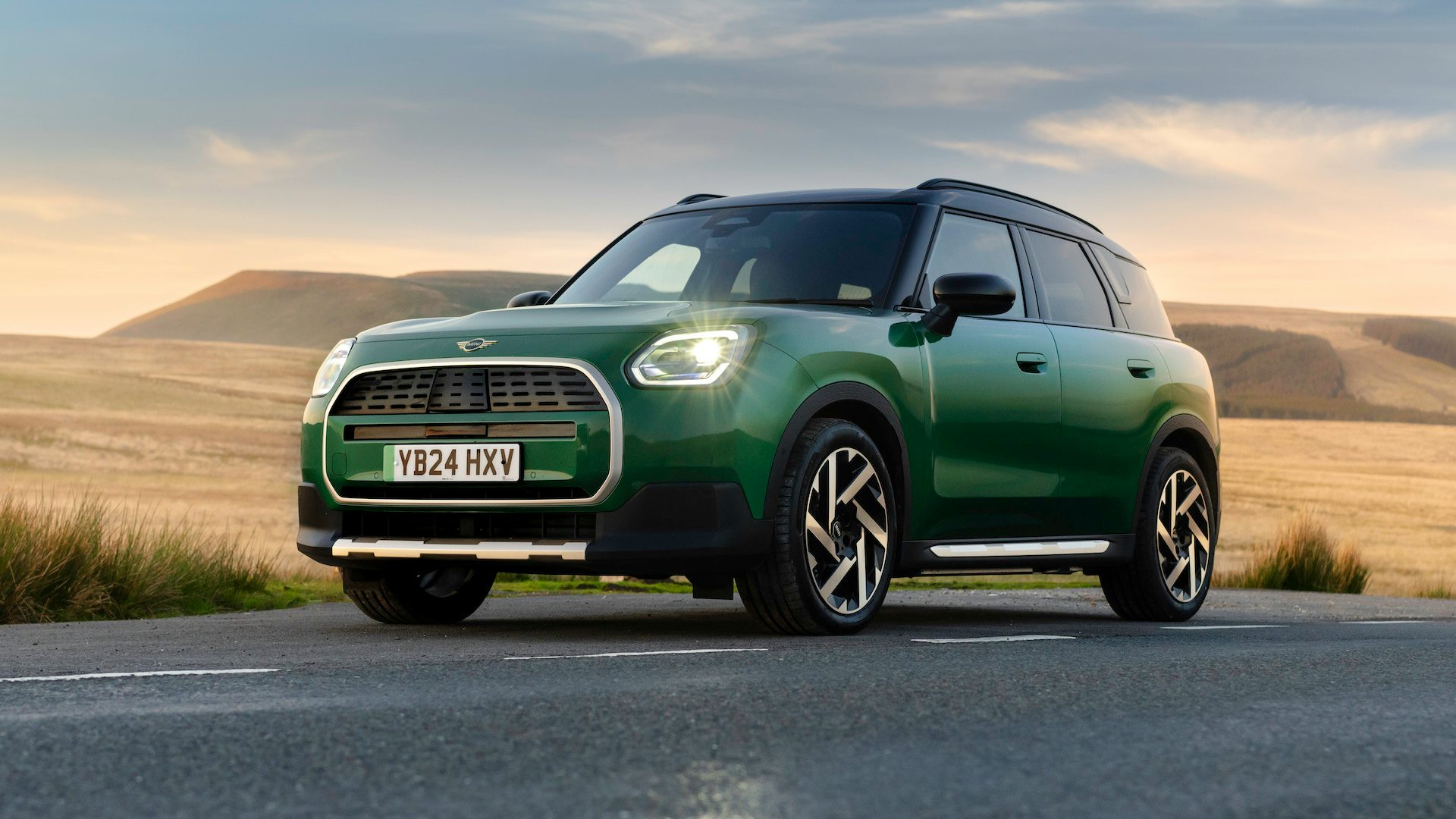 Green 2024 Mini Countryman Electric parked beside the road in a rural area, front quarter view.