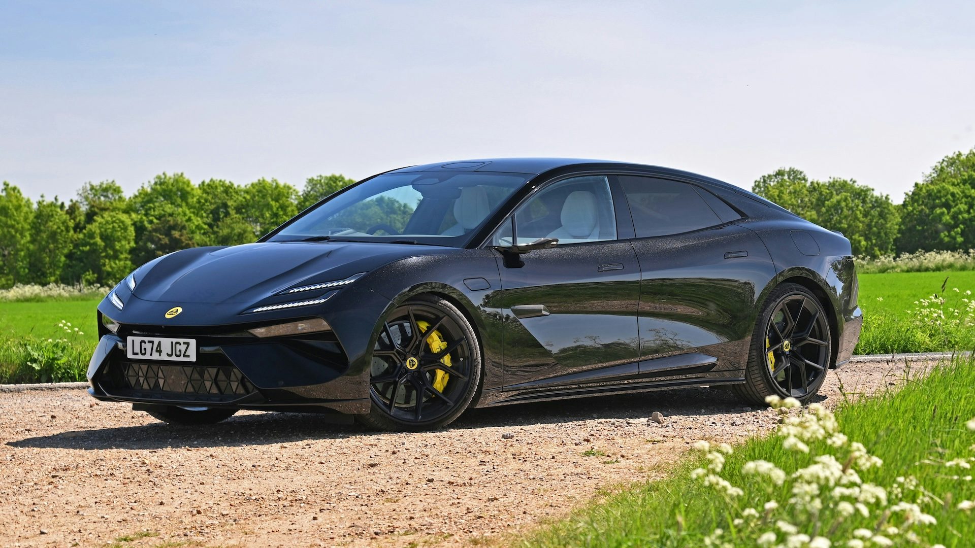 Black 2025 Lotus Emeya parked on gravel, front quarter angle.