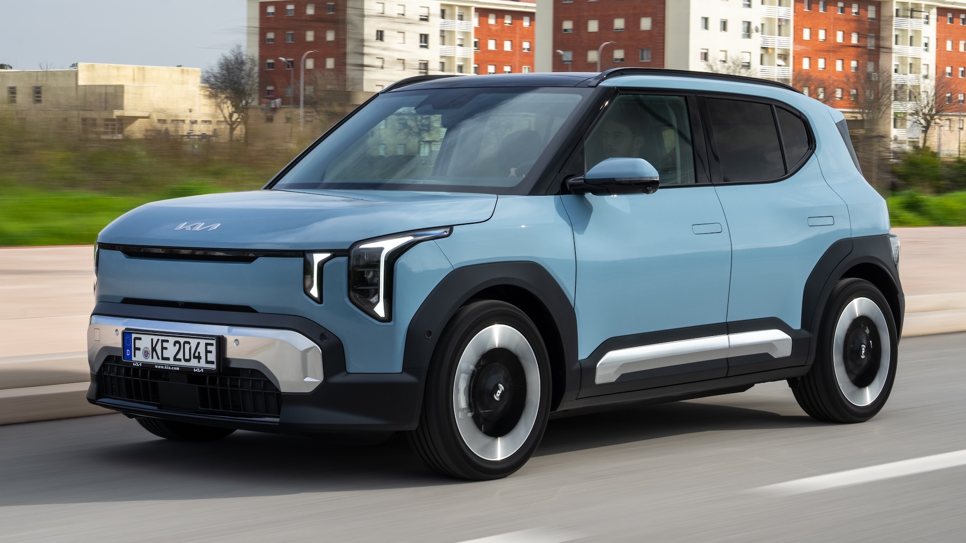 Blue 2026 Kia EV2 driving in the city, front quarter.