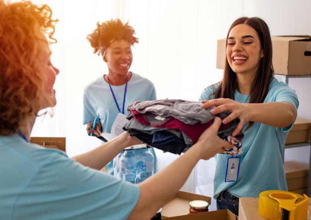 Female entrepreneurs helping other by giving out piles of clothing