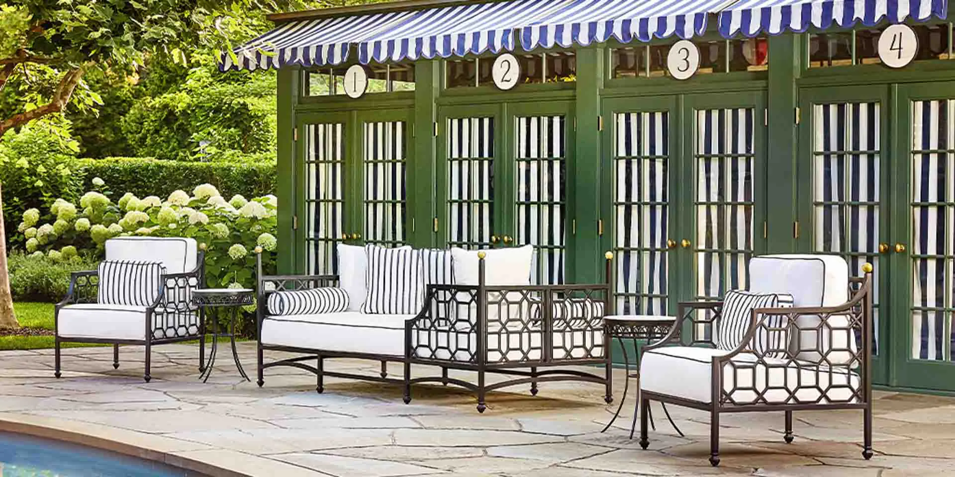 Stylish poolside lounge chairs and sofa in backyard Hamptons setting.