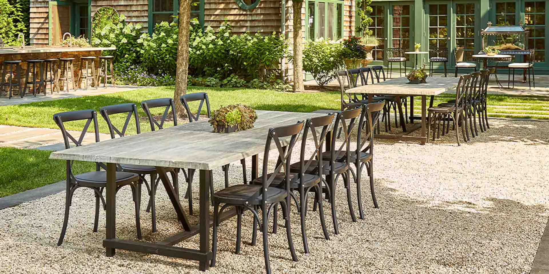 Outdoor dining ensemble with tables and chairs in garden setting.