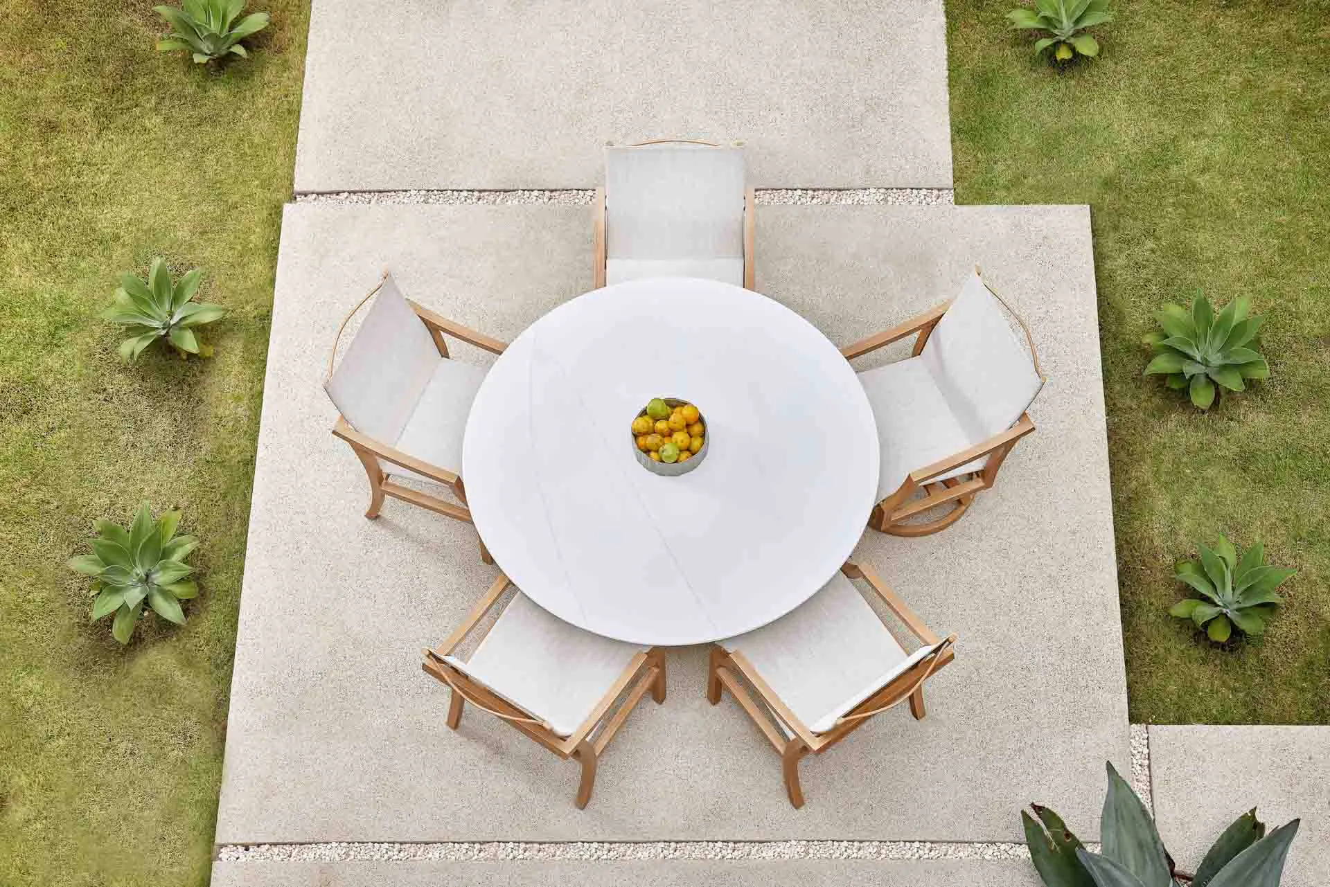 Aerial shot of circular dining table and an assortment of chairs in outdoor setting.