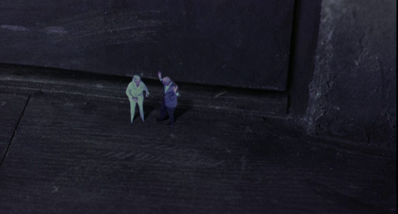 Two minature figures standing in front of a door.