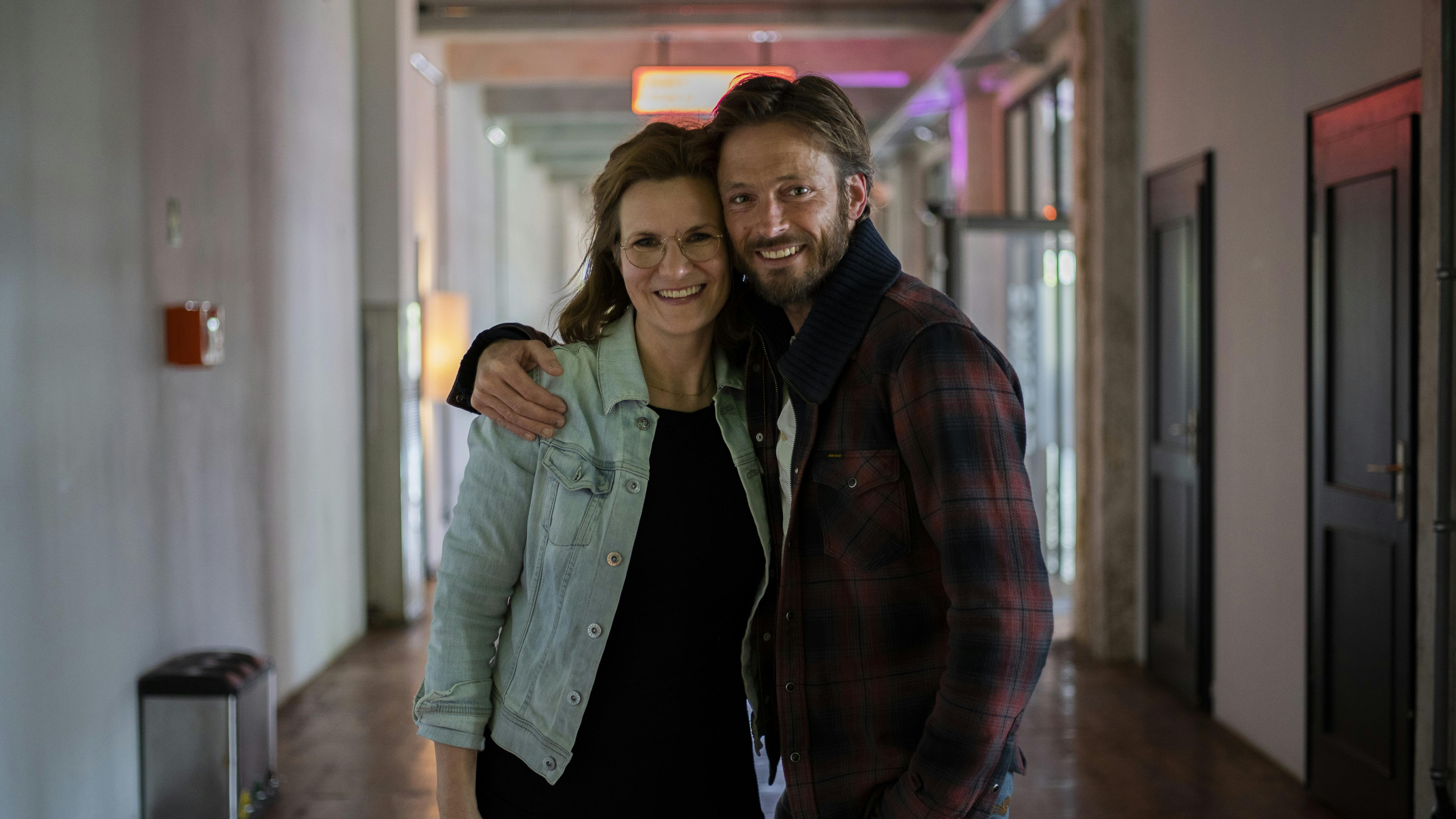 Andreas Pietschmann and Sylvia Schwarz in the catalyst hallway, smiling towards the camera and hugging each other