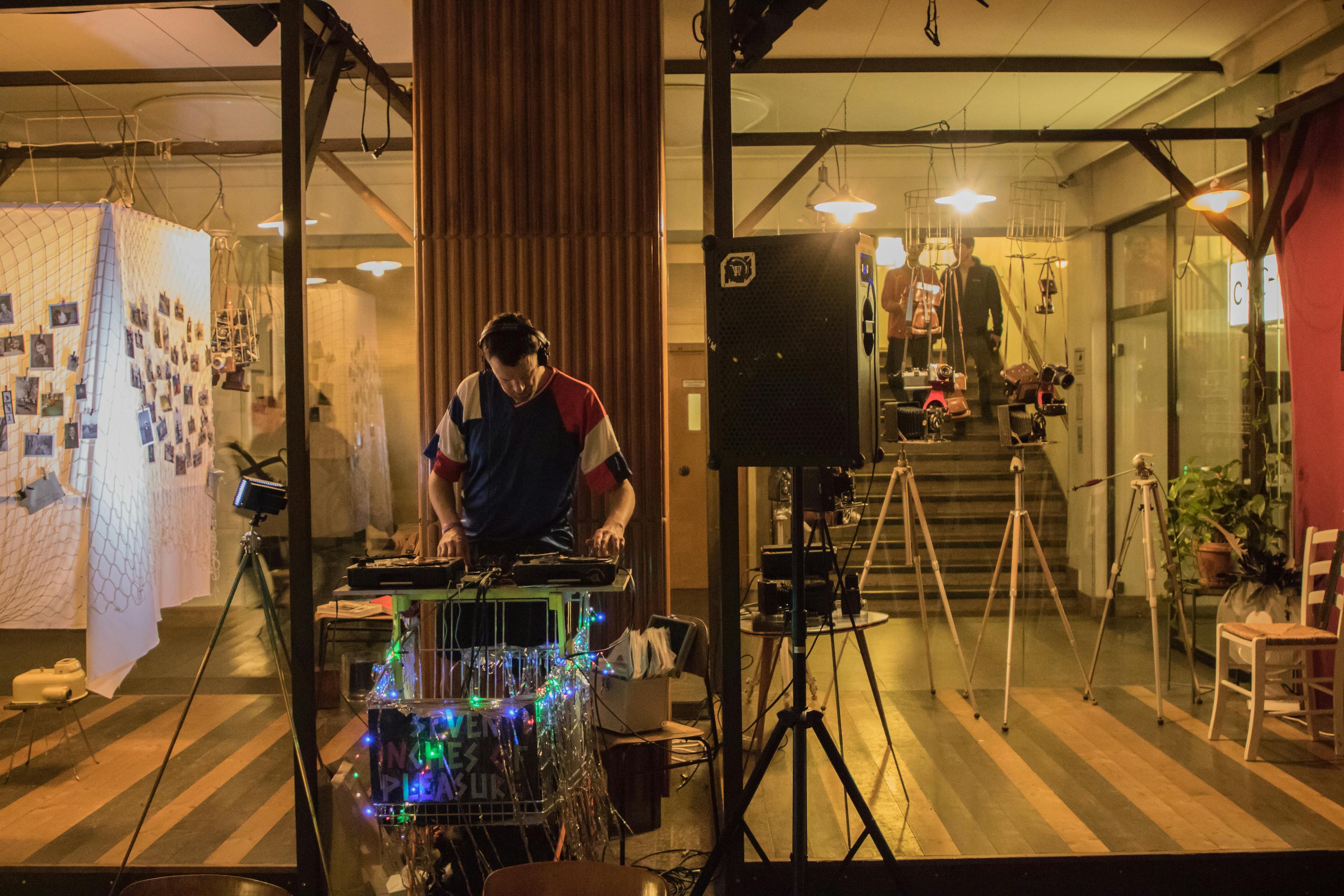 DJ spinning 7inch records in John Waldron's installation, Gitti's Wake. The DJ performs from a shopping trolley, he is surrounded by a photography installation