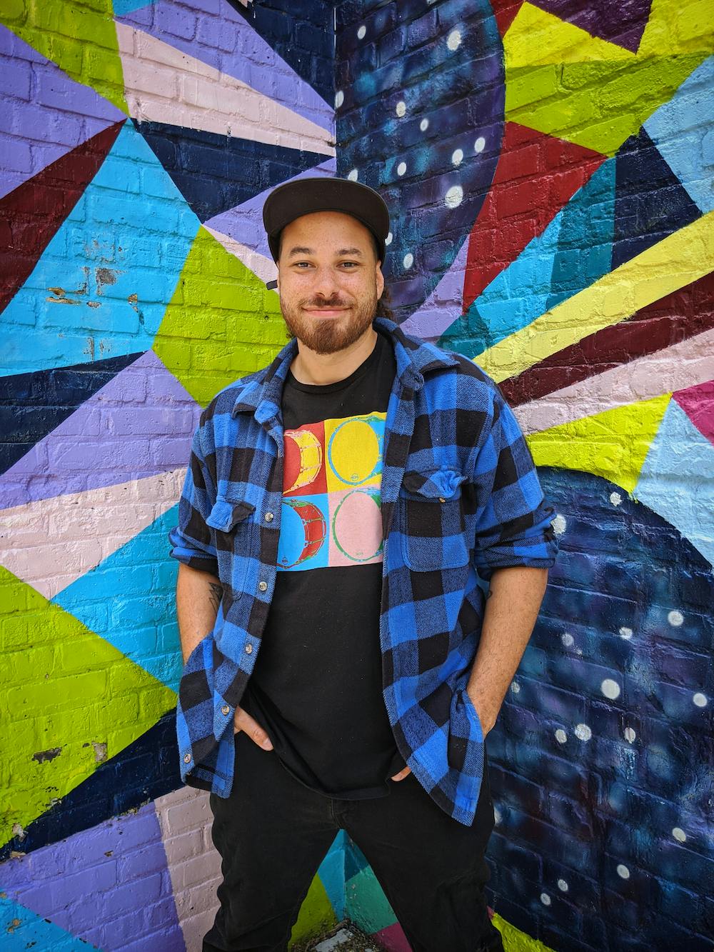 Student Wellbeing Champion Cordelle Glass smiles infront of colourful graffiti
