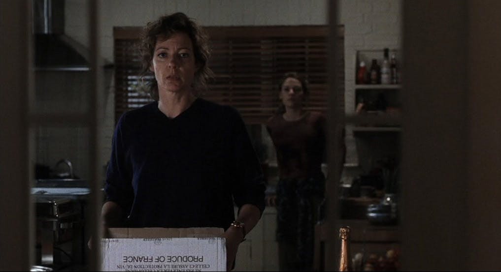 A woman holding a box looking through a doorway