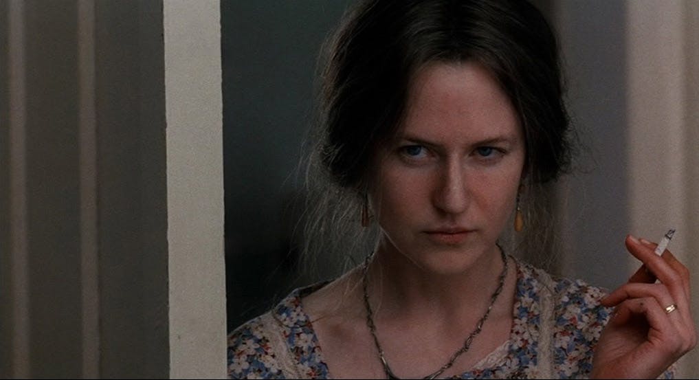 Julianne Moore smoking a cigarette in a doorway.