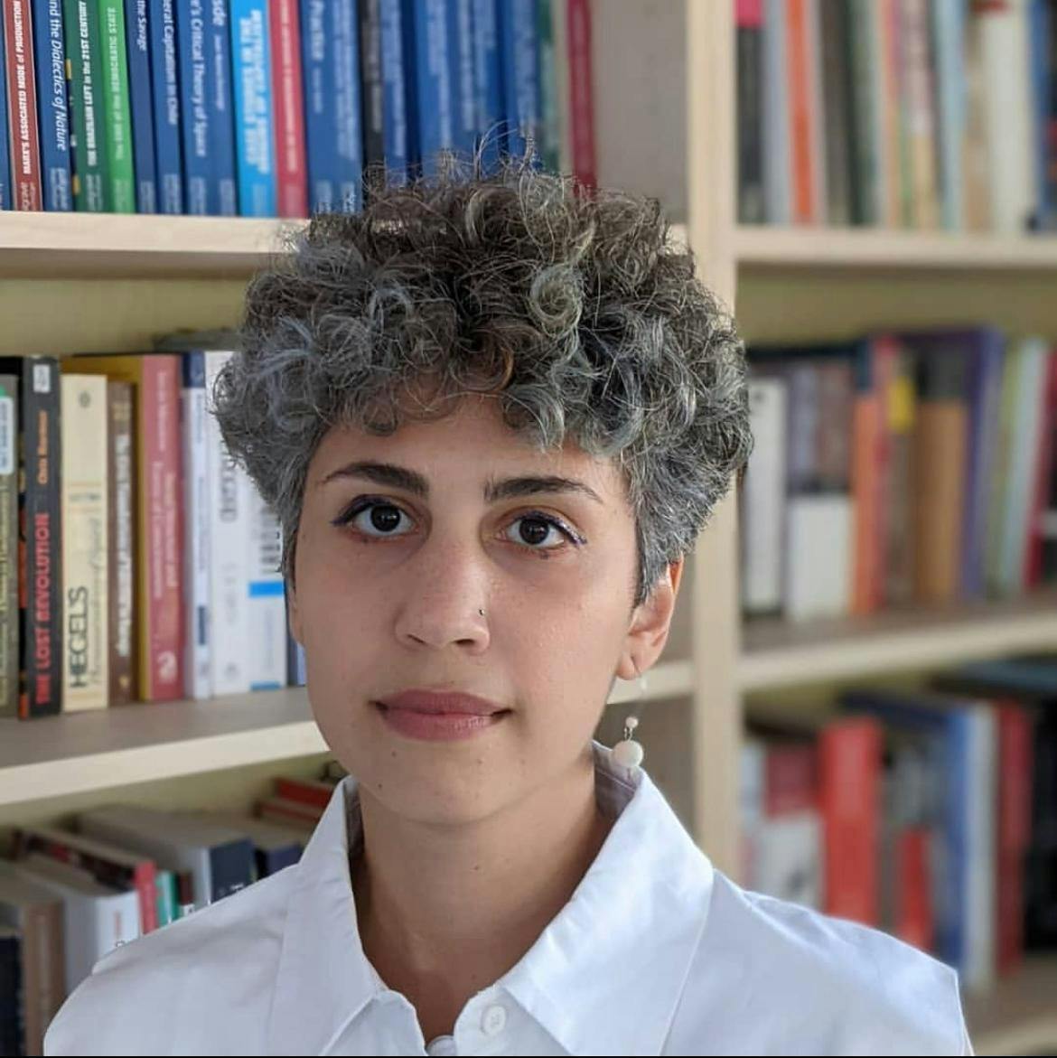 Catalyst tutor Roshanak Amini infront of shelves full of books