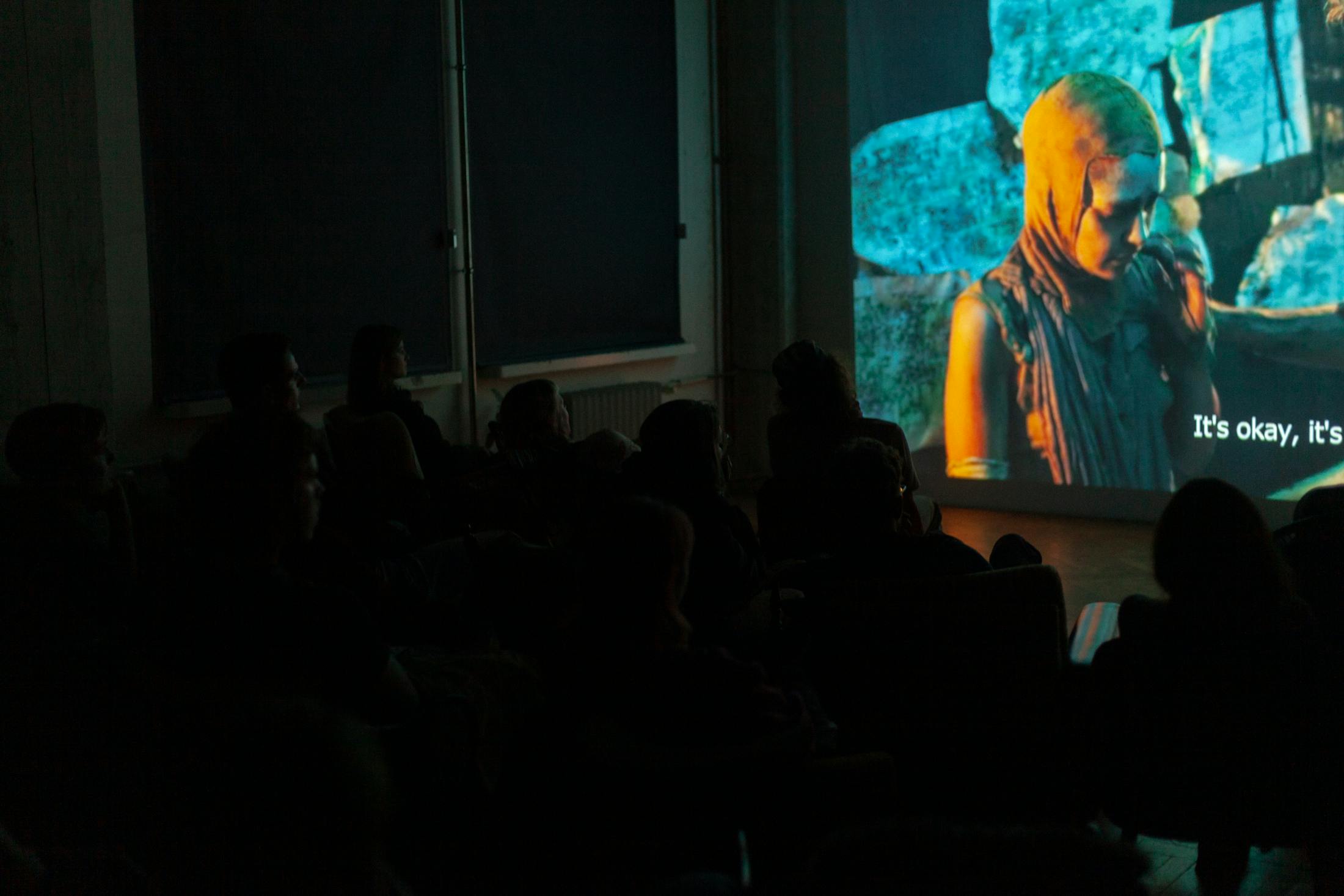 An audience watches a film screening in a blacked out room at Signals Festival