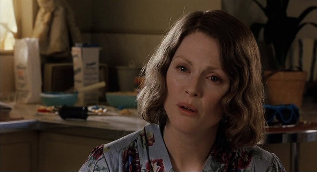 Nicole Kidman sits at a kitchen table, looking upset