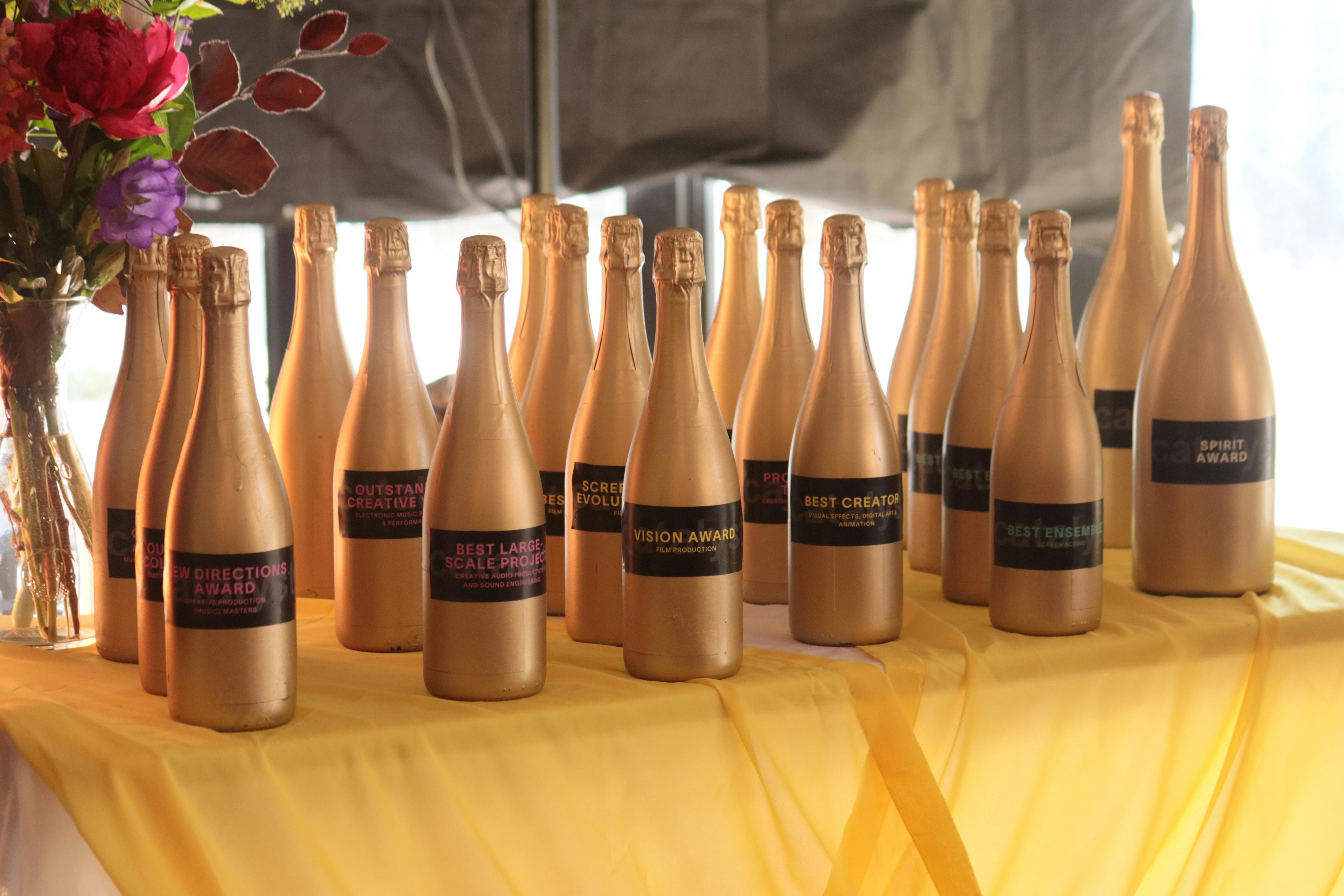 Gold award bottles displayed on a yellow table at The Catties