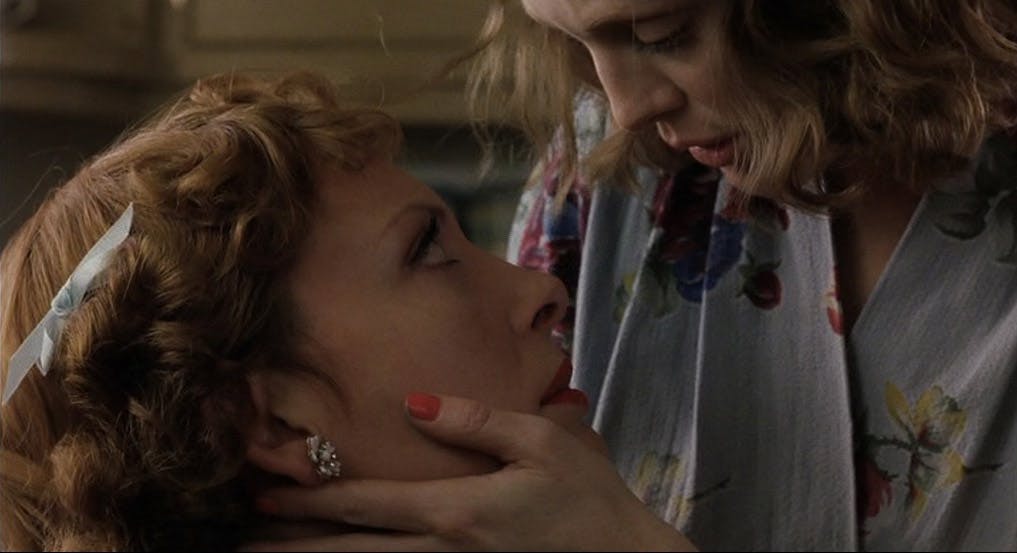 A woman gently caresses another woman's face.
