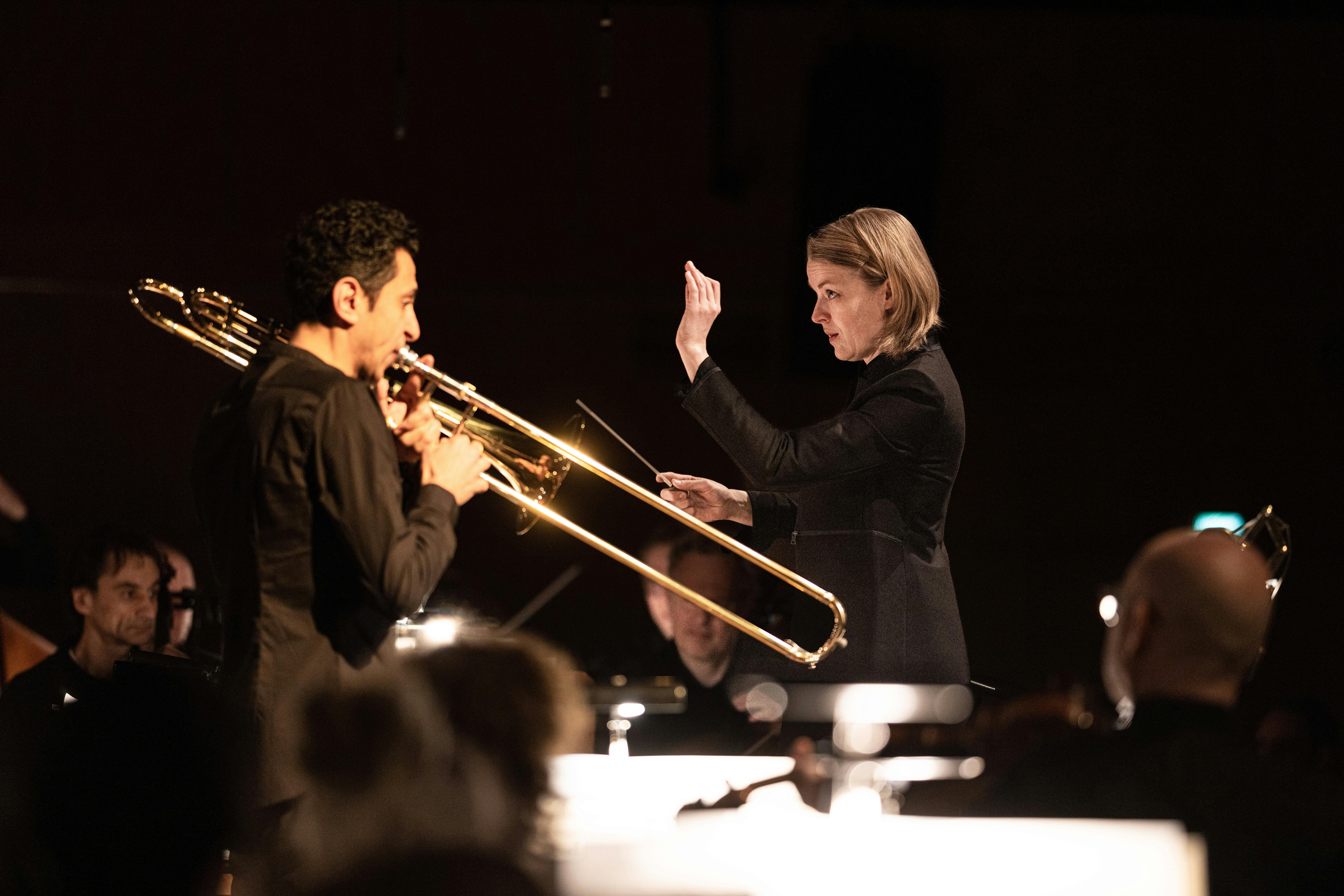 Conductor commands while man plays trombone 