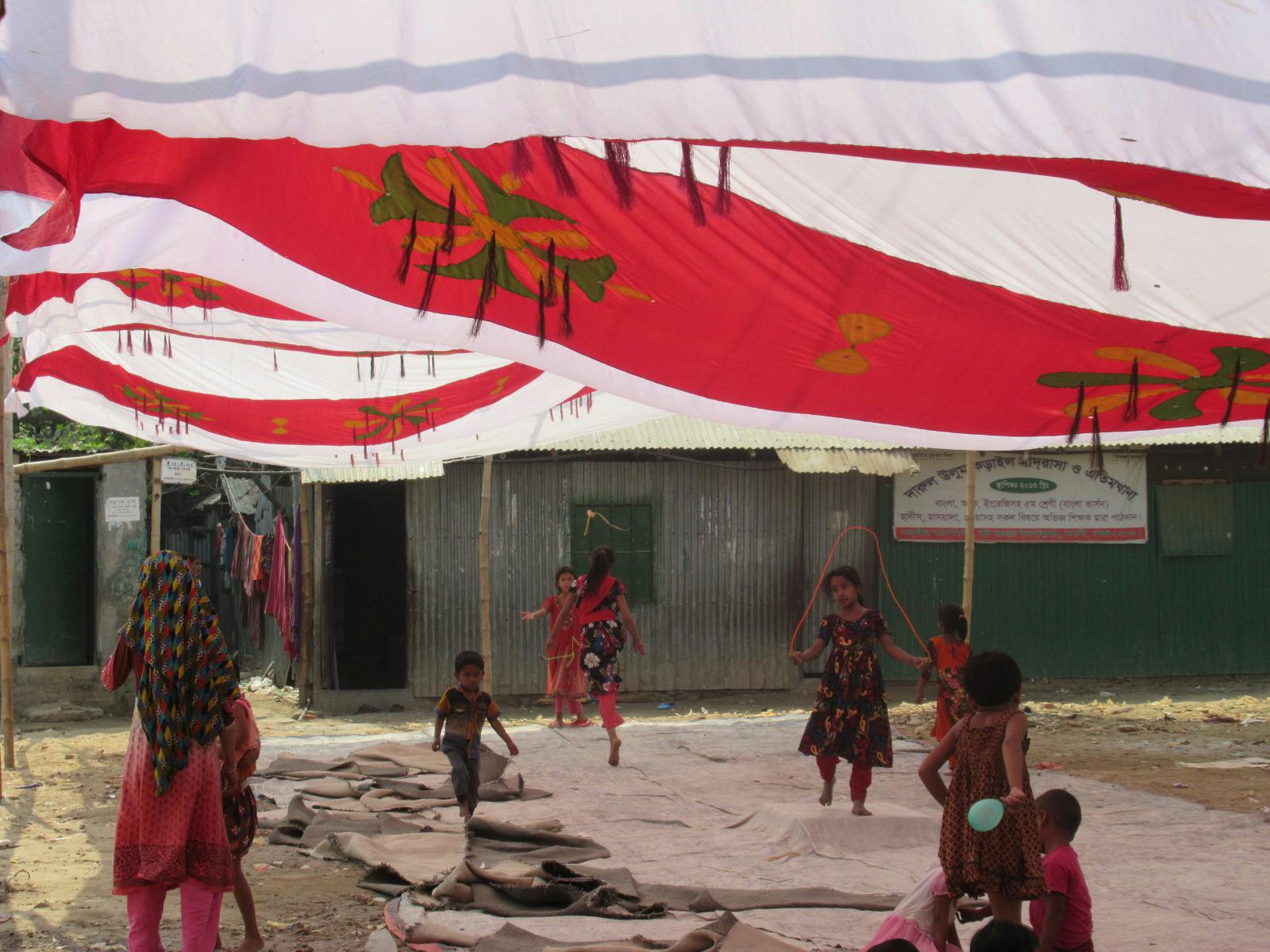 Still from Wherever I Am, the Sky Is Mine, around 8 children are playing under some fabric