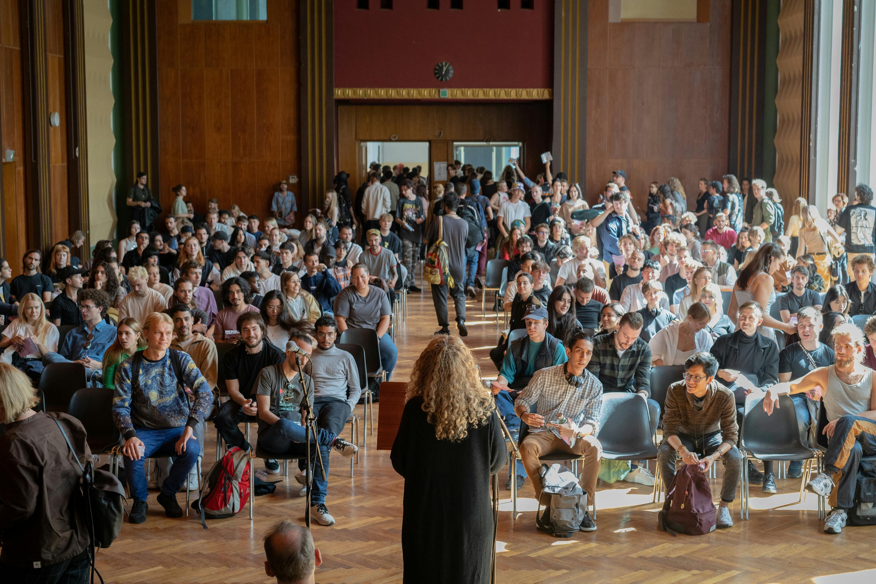 tutor stands in front of a full hall of students