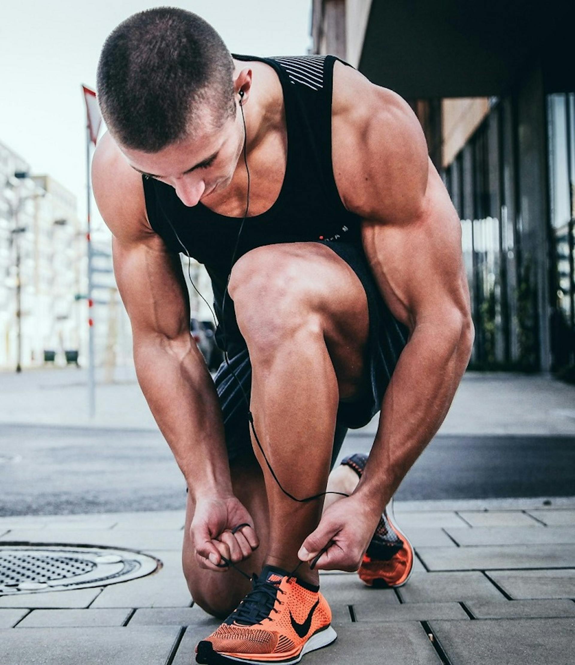 athlete on footpath tying laces of his runners