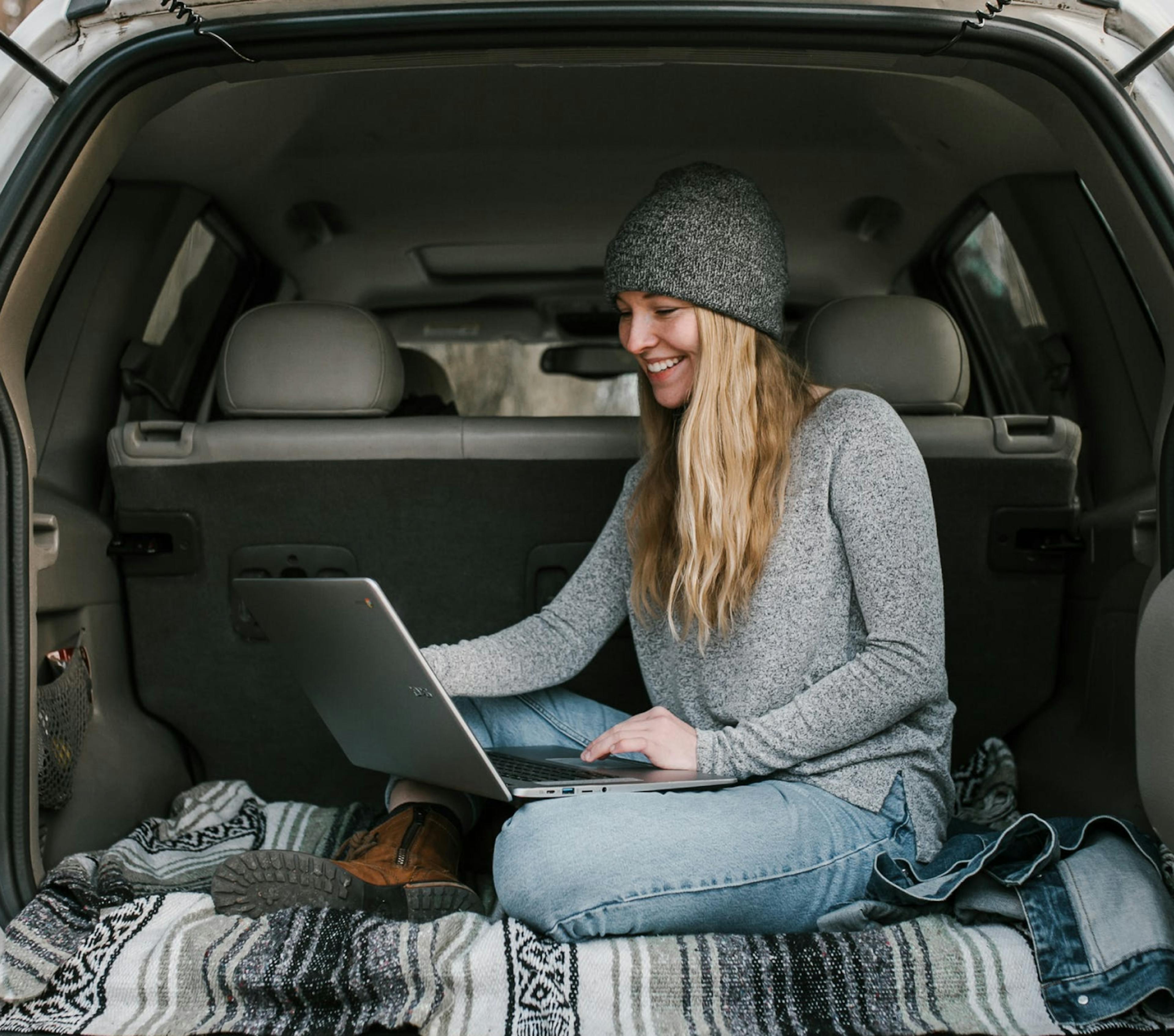 women in car using laptop