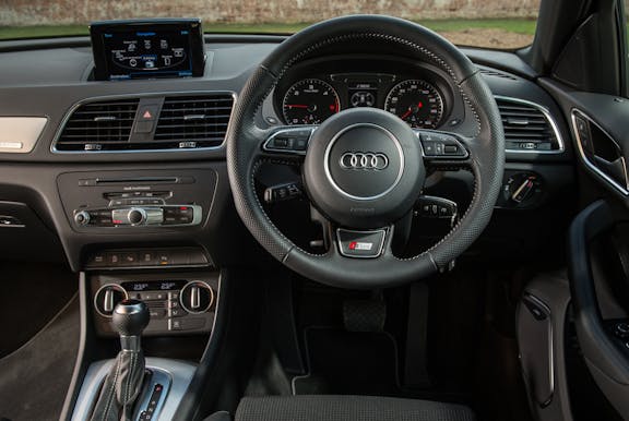 The interior of an Audi Q3 with steering wheel and dashboard in shot