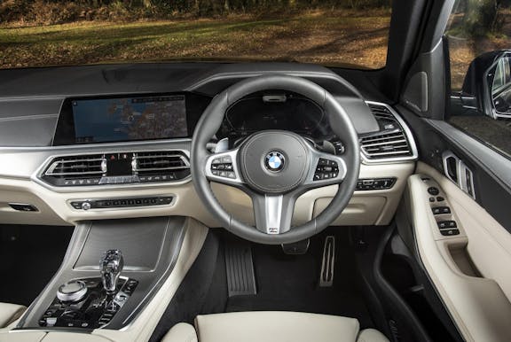 The interior of a BMW X5 with steering wheel and dashboard in shot