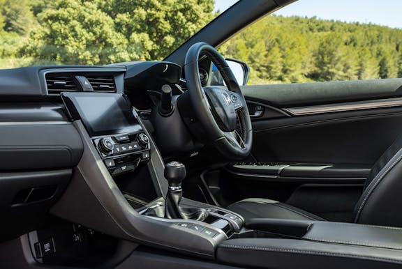 The interior of a Honda Civic with steering wheel and dashboard in shot