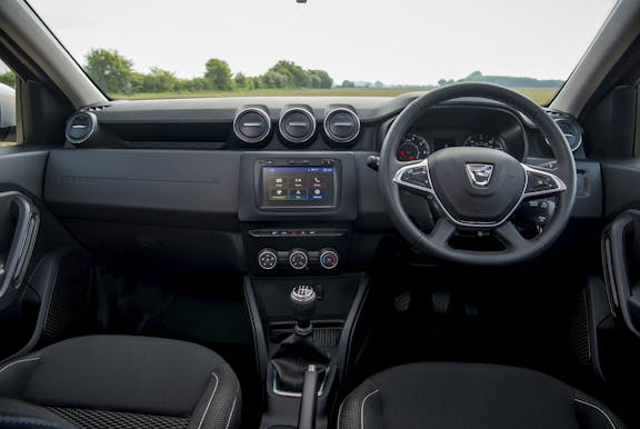 The interior of a Dacia Duster with steering wheel and dashboard in shot