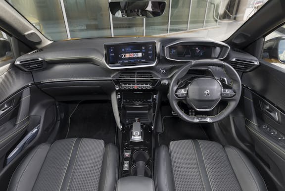 The interior of a Peugeot 208 with steering wheel and dashboard in shot