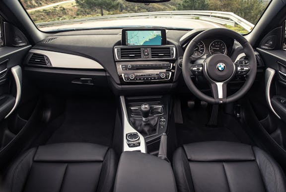 The interior of a BMW 2-Series with steering wheel and dashboard in shot