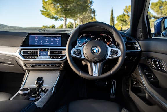 The interior of a BMW 3 Series with steering wheel and dashboard in shot