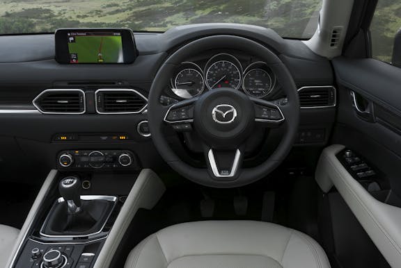The interior of a Mazda CX-5 with steering wheel and dashboard in shot