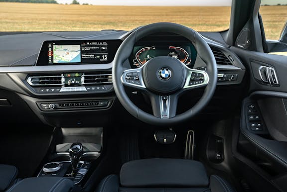 The interior of a BMW 1 Series with steering wheel and dashboard in shot
