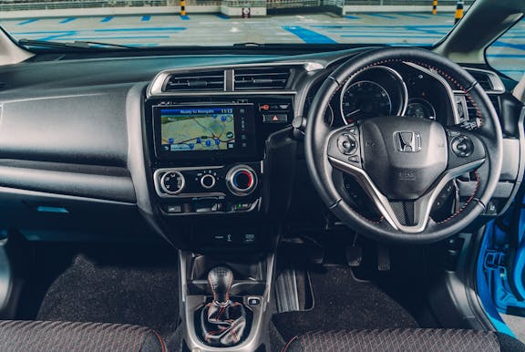 The interior of a Honda Jazz with steering wheel and dashboard in shot