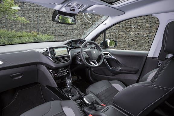 The interior of a Peugeot 2008 with steering wheel and dashboard and front seat in shot