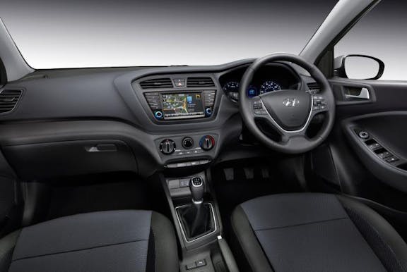The interior of a Hyundai i20 with steering wheel and dashboard in shot